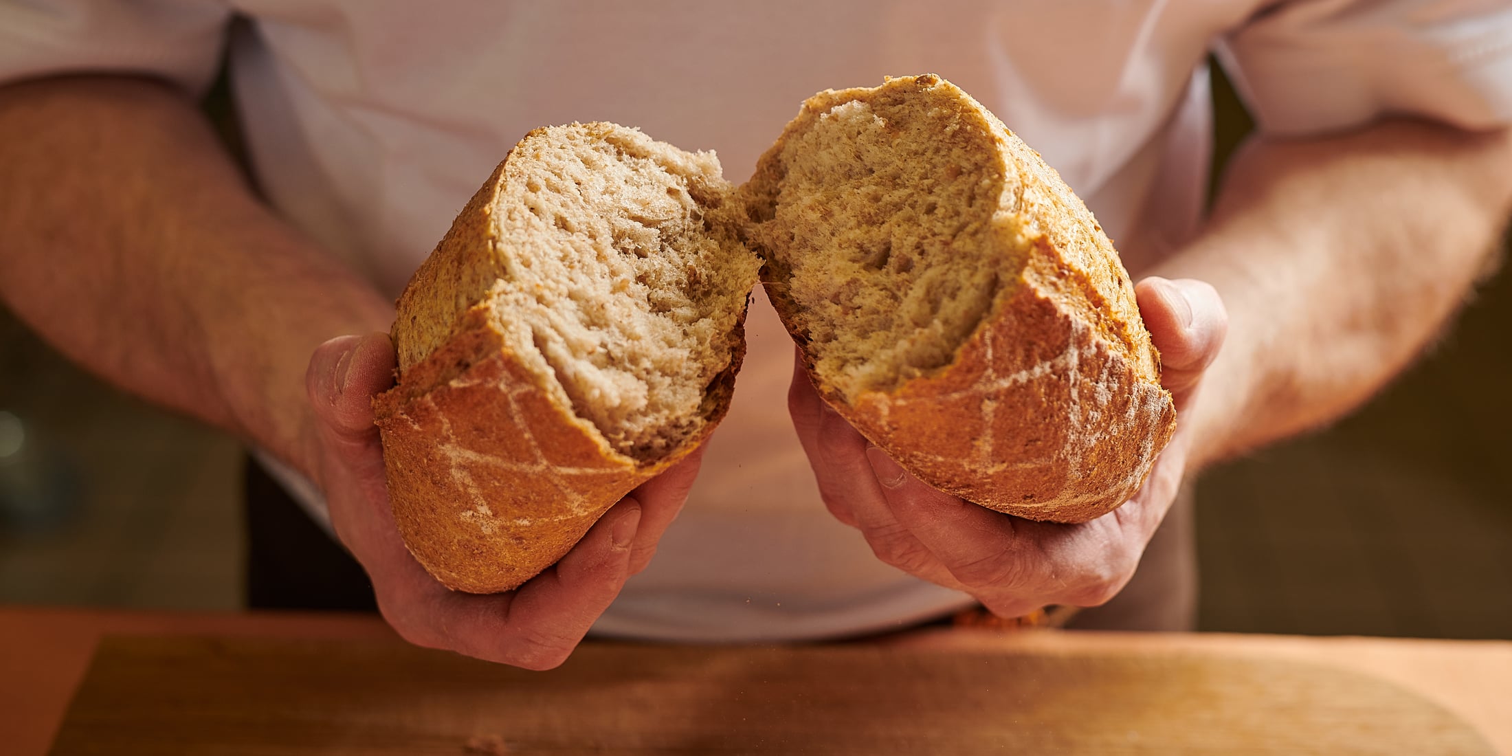 Bäcker zeigt in zwei Hälften geschnittenes Brot
