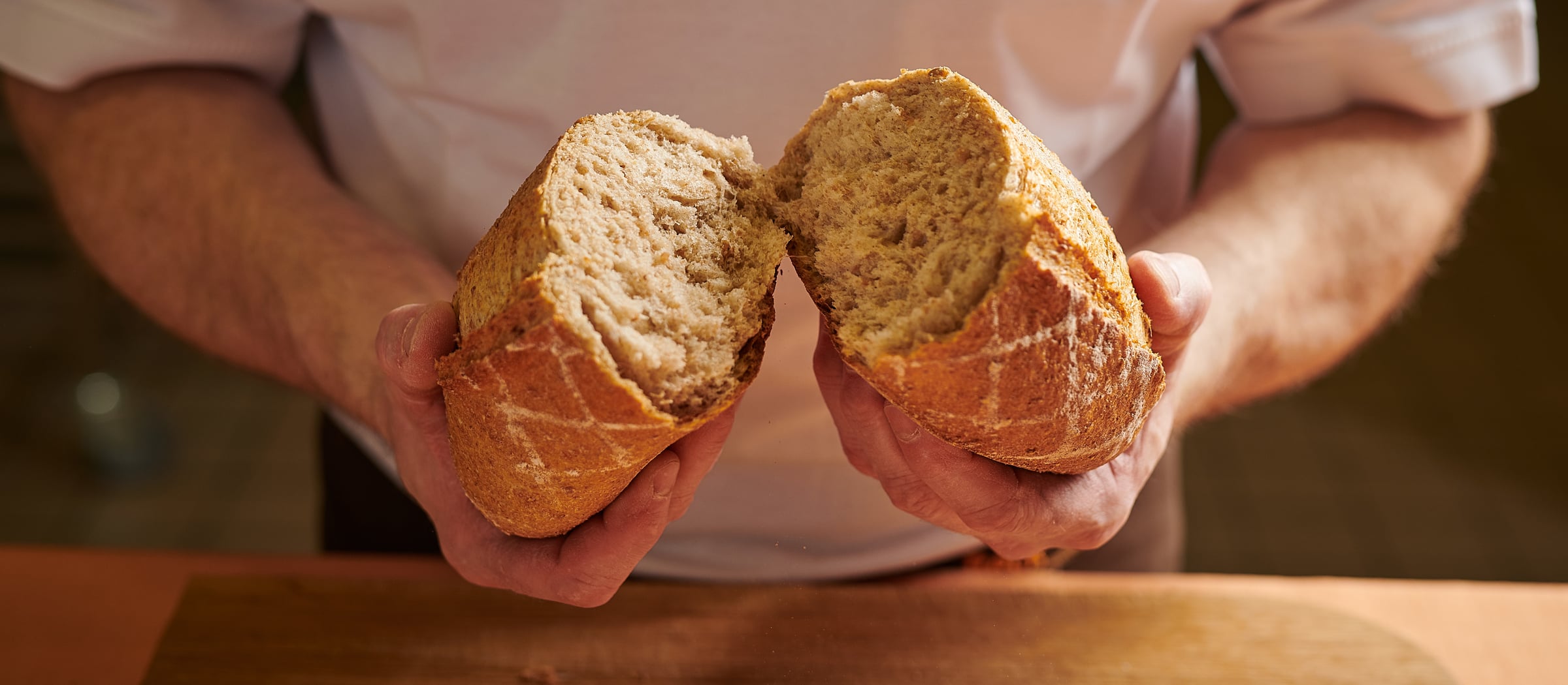 Bäcker zeigt in zwei Hälften geschnittenes Brot