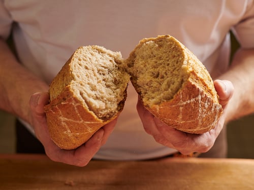 Bäcker zeigt in zwei Hälften geschnittenes Brot